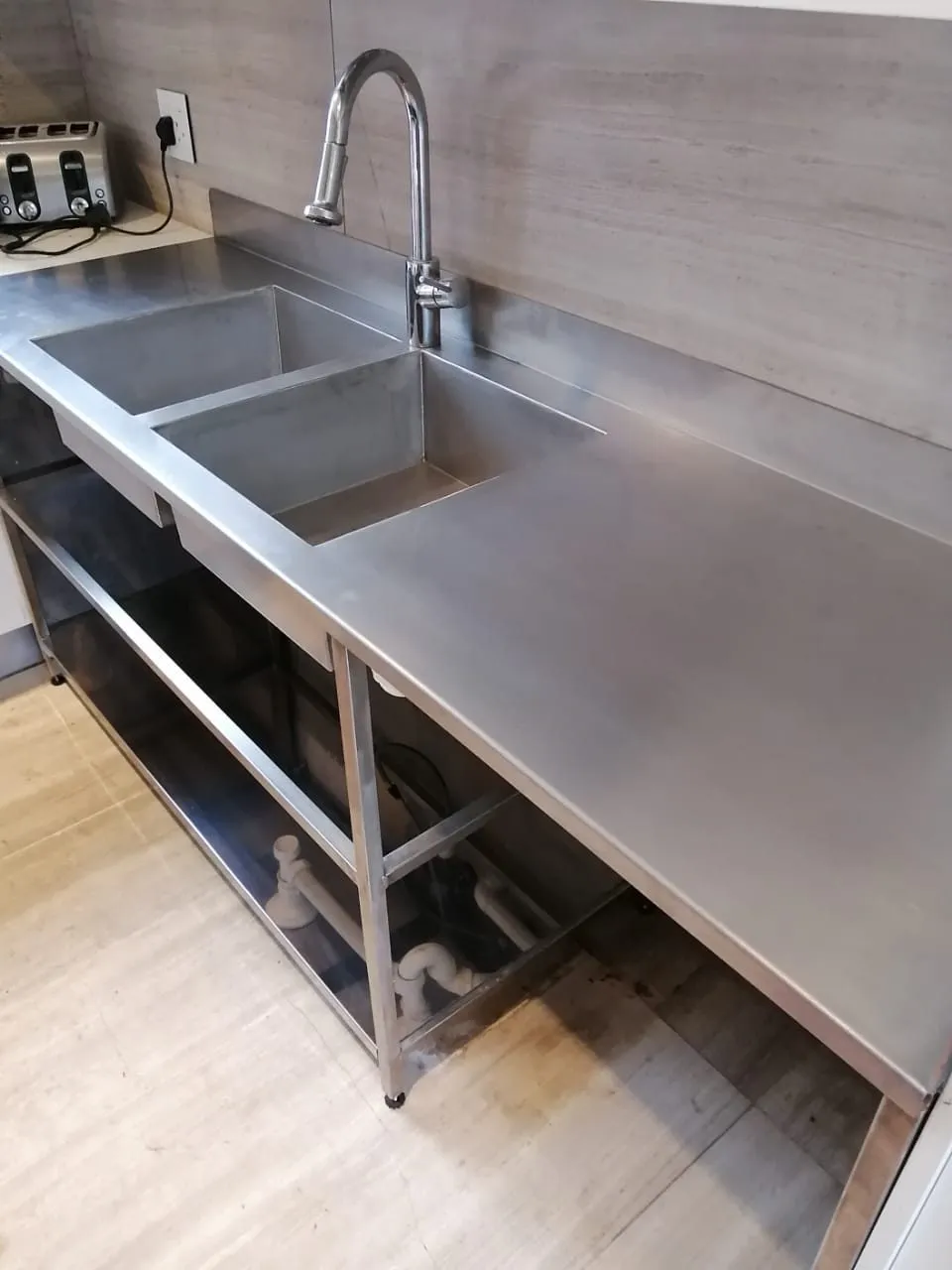 Stainless steel double bowl sink with drainer and undershelf, fitted in a kitchen
